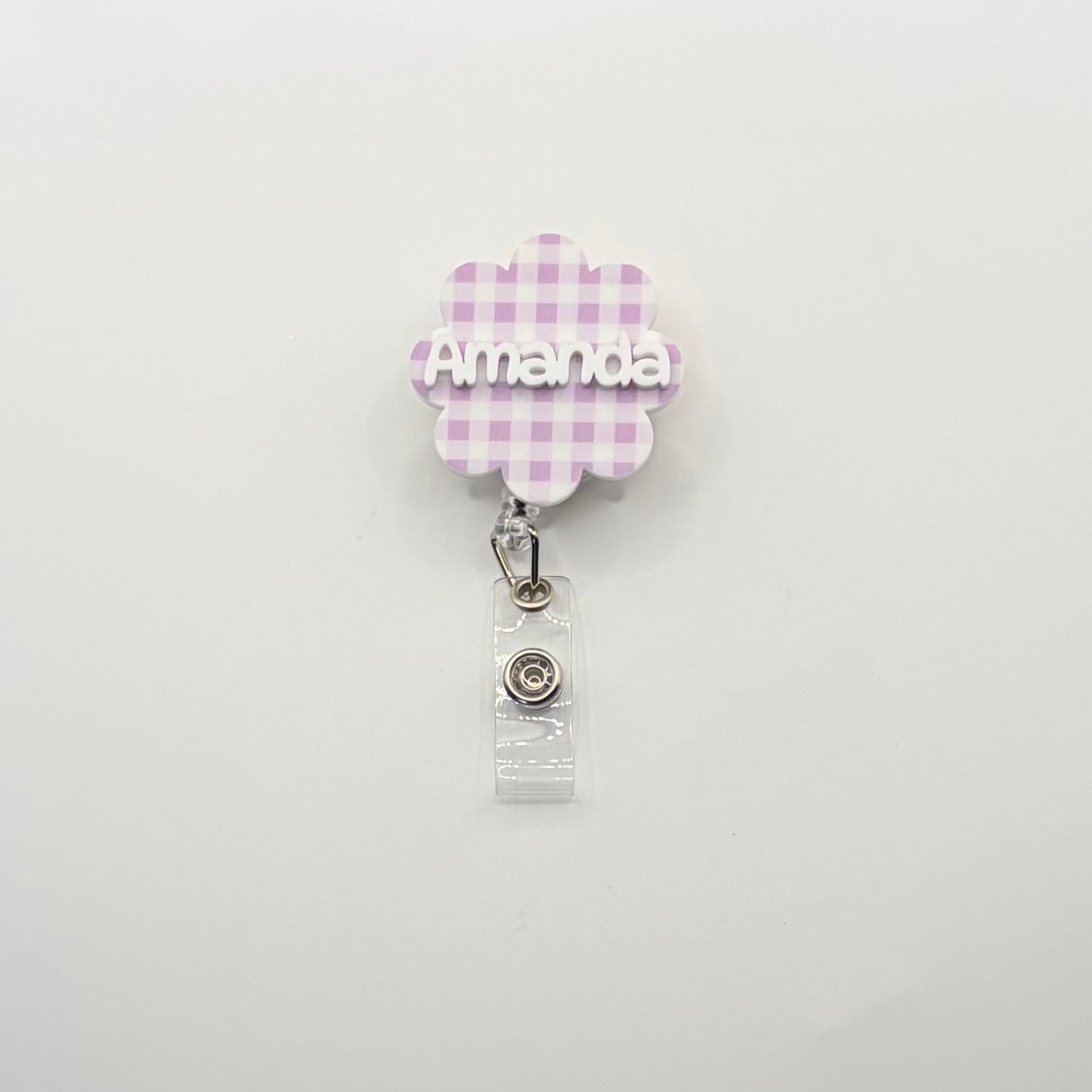 Retractable badge holder with 'Amanda' on a checkered flower design on a white background