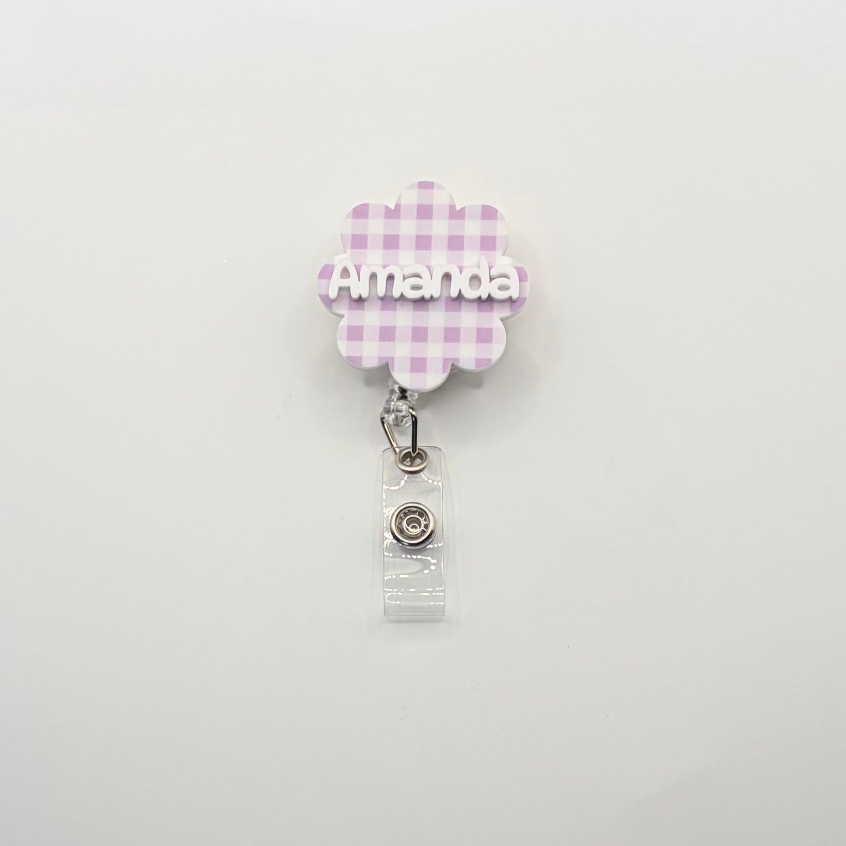 Retractable badge holder with 'Amanda' on a checkered flower design on a white background